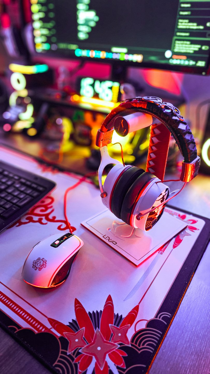 Cuffie da gaming e mouse su una scrivania con luci luminose.